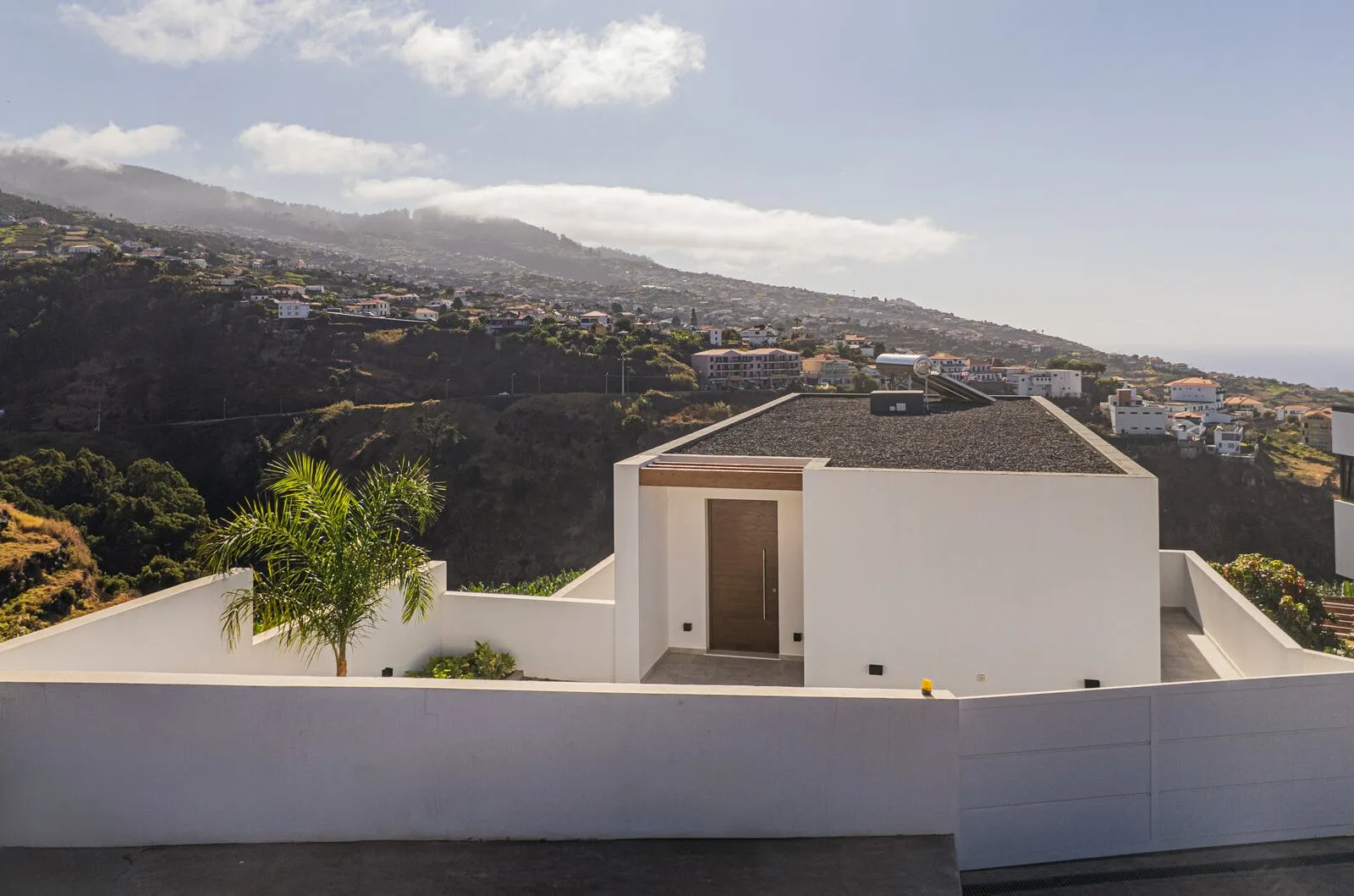 White house on a green Madeira hillside near the edge of low cloud